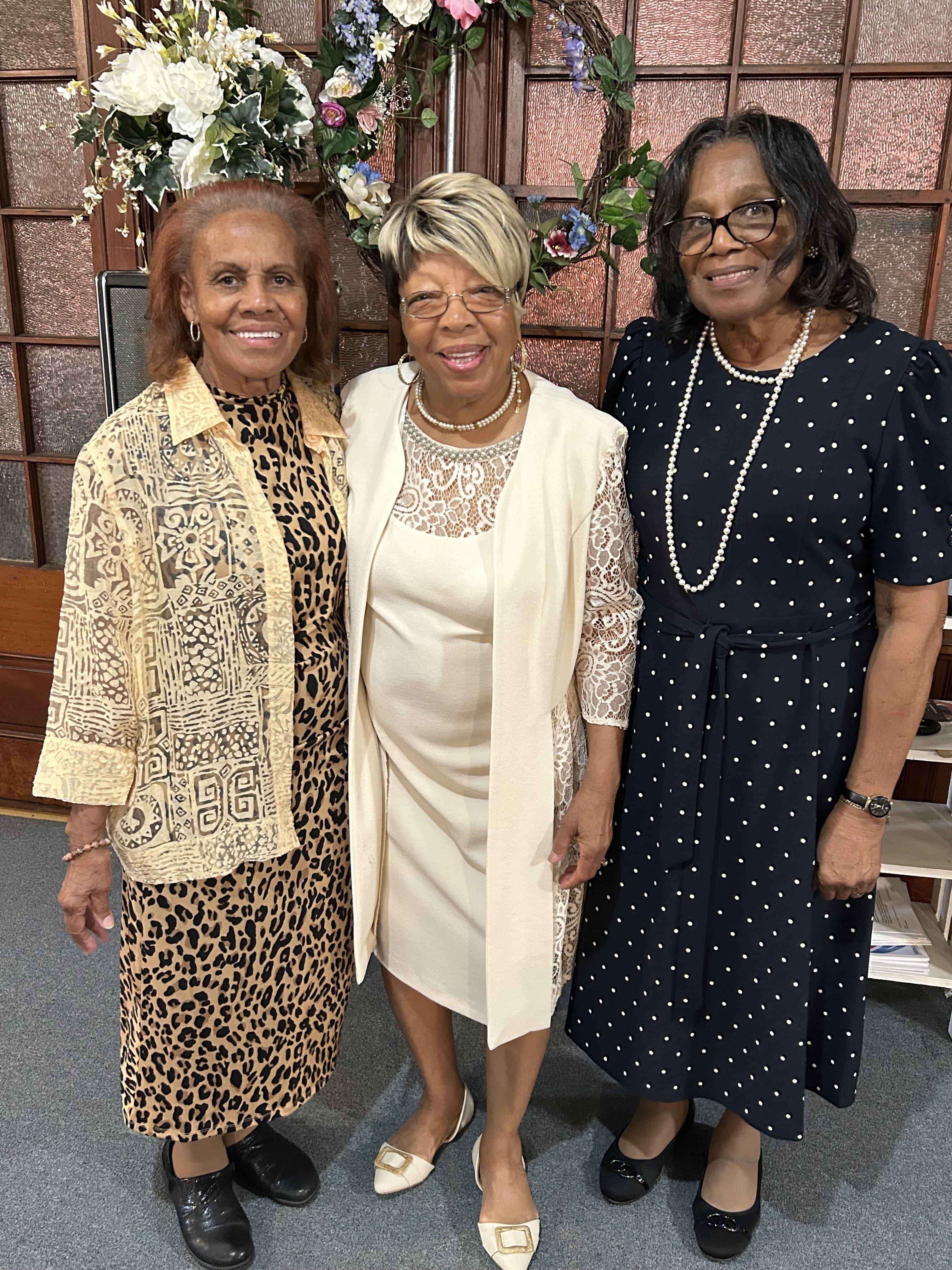 Three church mothers standing together in the sanctuary